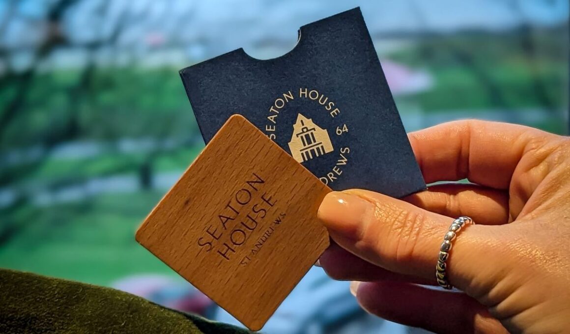 Seaton House St Andrews room key and wooden key card with coastal view in background.