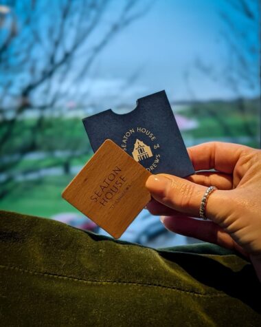 Seaton House St Andrews room key and wooden key card with coastal view in background.