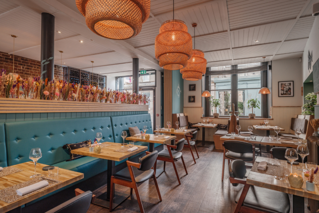 Dulse Leith restaurant interior with teal banquette seating, wooden tables, woven pendant lights and colourful dried flowers.